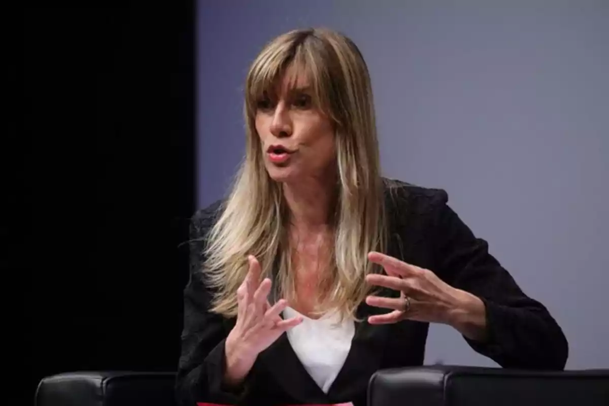 A woman speaking gesturing with her hands on a stage.