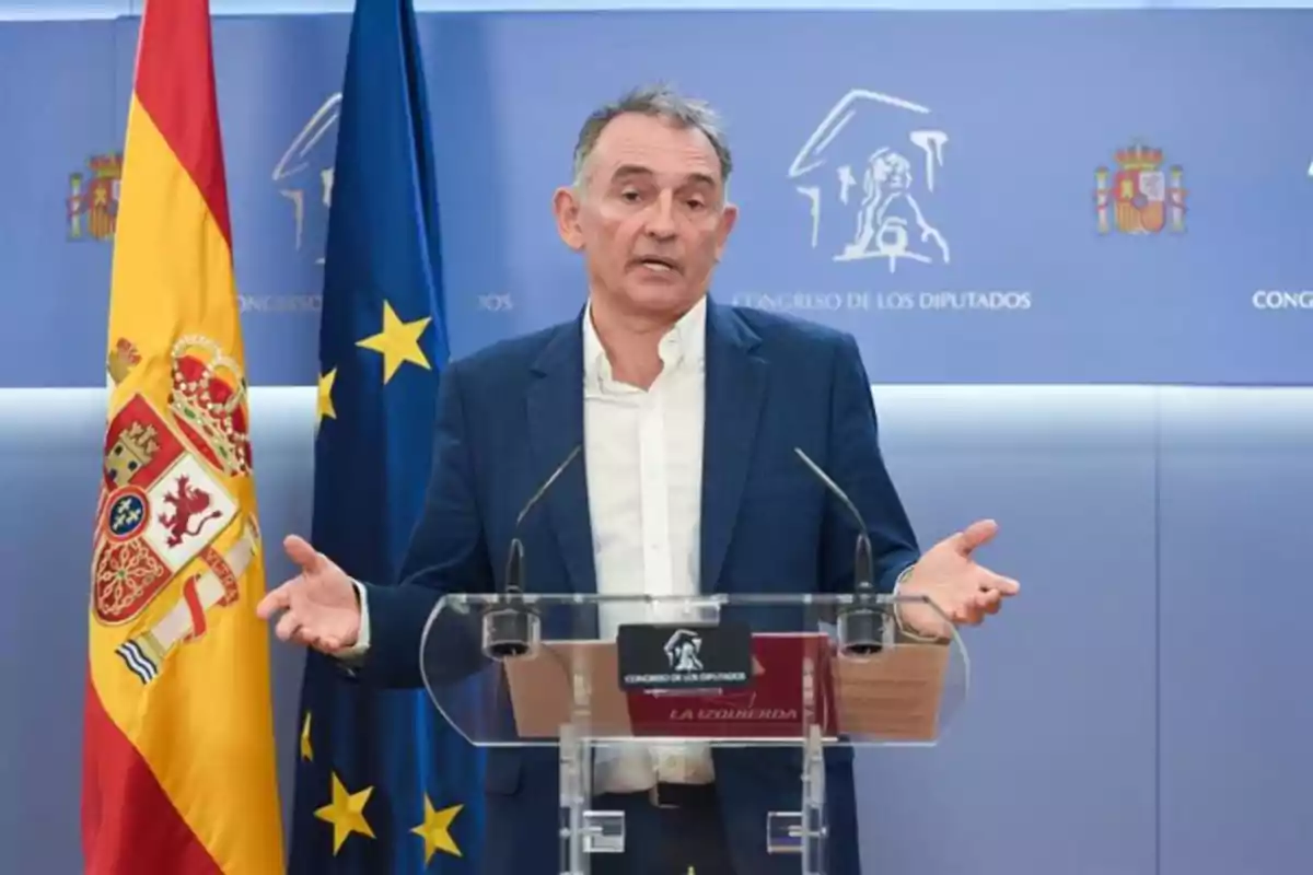 Hombre de mediana edad hablando en una rueda de prensa en el Congreso de los Diputados de España con banderas oficiales a su lado Hombre de mediana edad hablando en una rueda de prensa en el Congreso de los Diputados de España con banderas oficiales a su lado