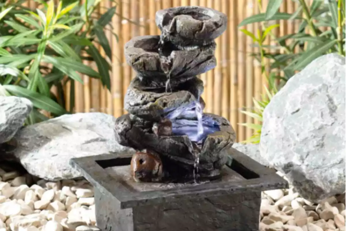 Fuente de agua decorativa con piedras apiladas y plantas de fondo. Fuente de agua decorativa con piedras apiladas y plantas de fondo.
