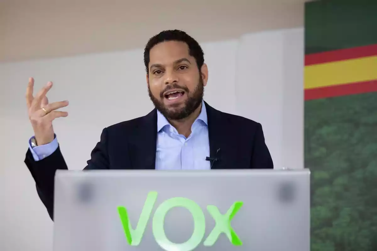 Hombre hablando en un podio con el logotipo de VOX.