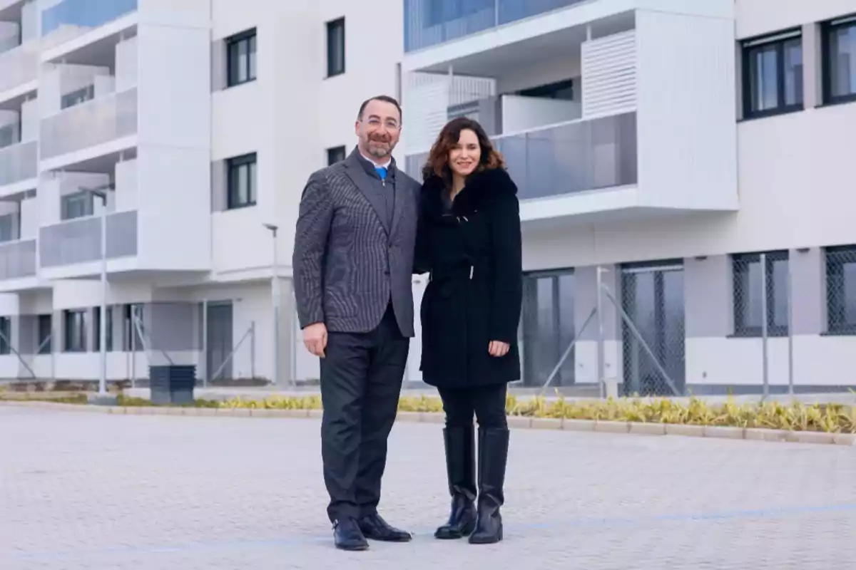 A couple posing in front of a modern building.