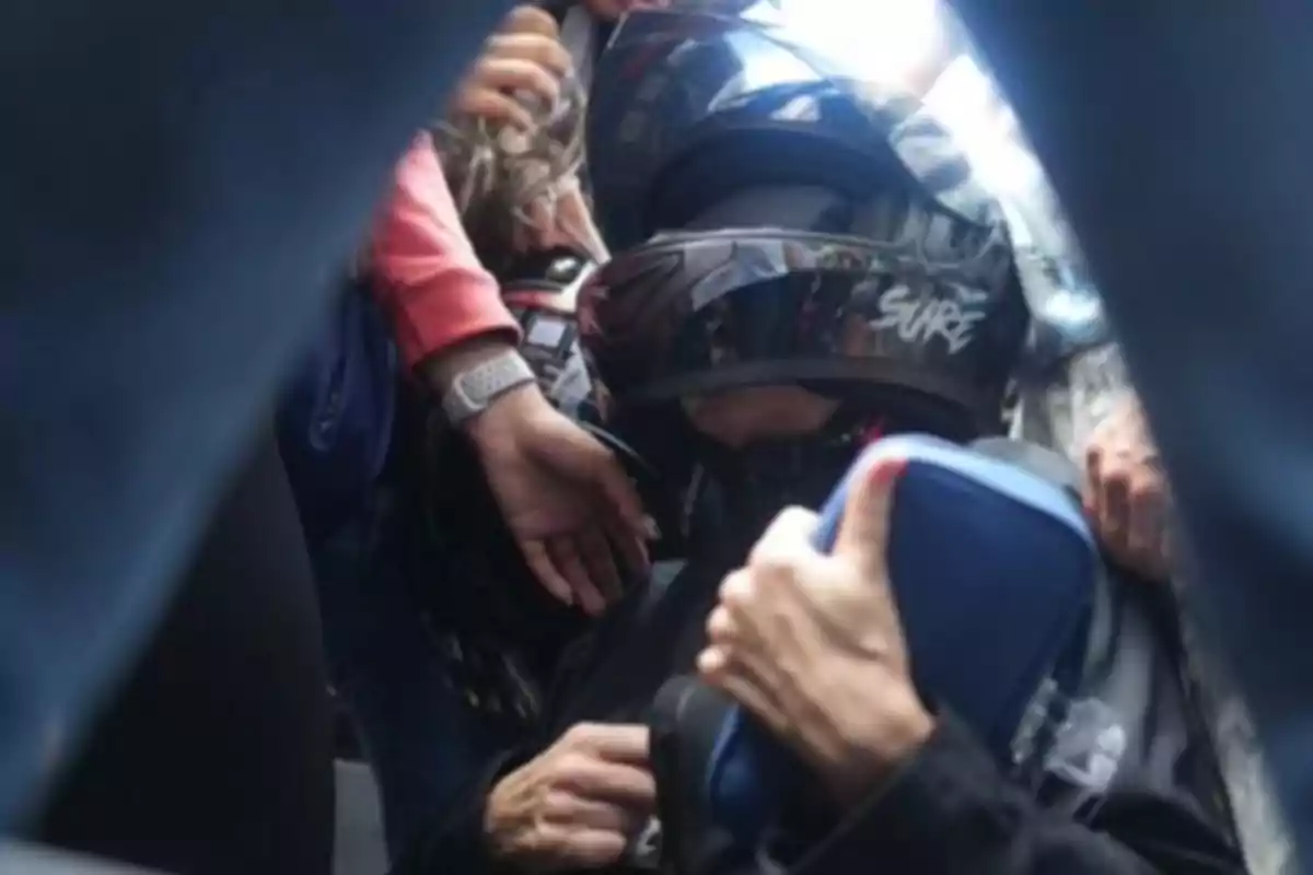 Persona con casco de motocicleta rodeada de otras personas en un espacio reducido.