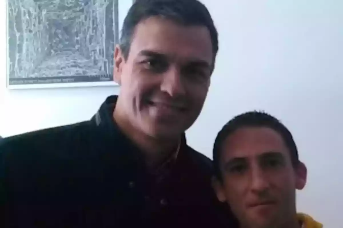Dos personas posan juntas para una foto en un interior con una pintura en la pared de fondo Dos personas posan juntas para una foto en un interior con una pintura en la pared de fondo