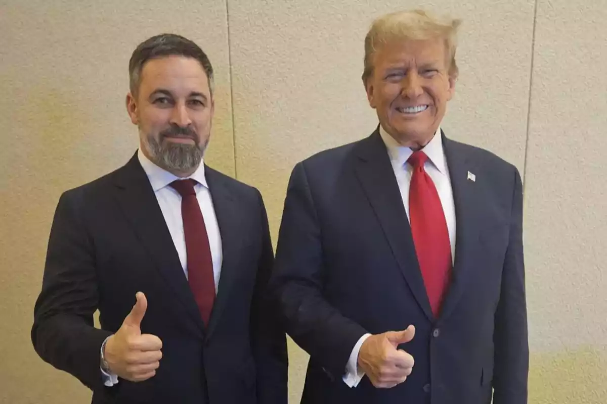 Dos hombres de traje oscuro y corbata roja posan sonriendo y levantando el pulgar. Dos hombres de traje oscuro y corbata roja posan sonriendo y levantando el pulgar.