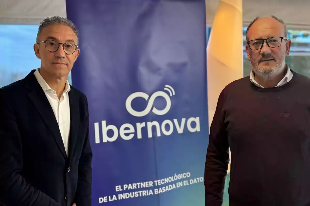 Dos hombres posan frente a un cartel de Ibernova que dice "El partner tecnológico de la industria basada en el dato".