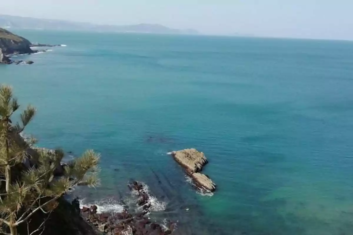 Vista panorámica de un acantilado con el mar azul y rocas en la costa.