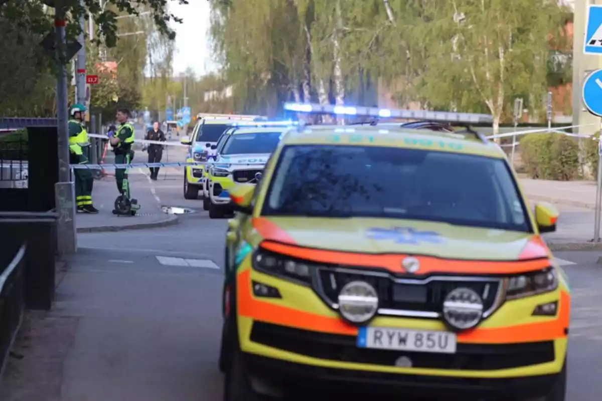 Una escena de emergencia en la calle con vehículos de policía y personal de seguridad.