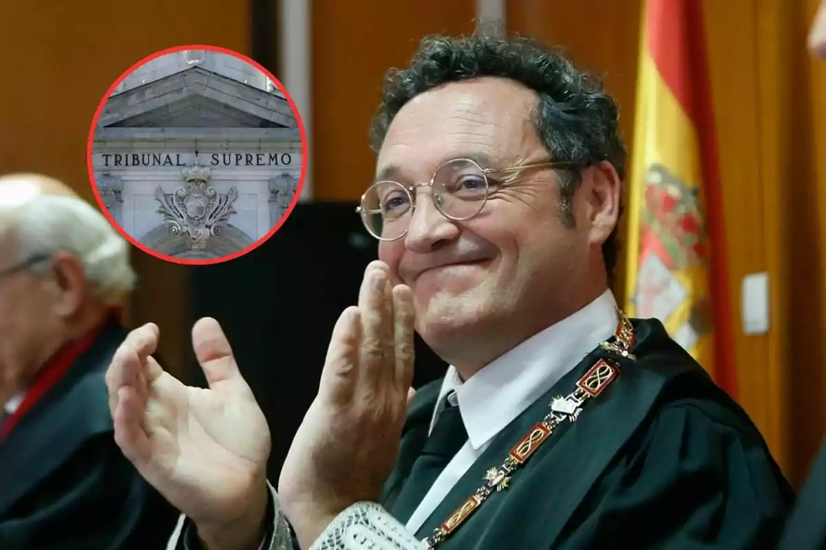 Un hombre con toga y medalla sonríe y aplaude en un evento oficial con una bandera de España al fondo y un recuadro que muestra la fachada del Tribunal Supremo.