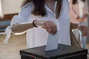 Persona depositando un sobre en una urna de votación.