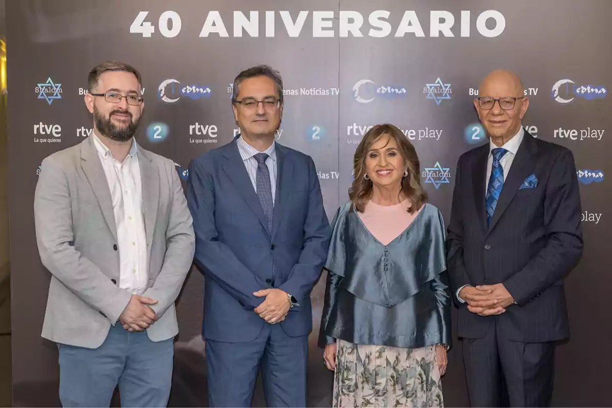 Cuatro personas posan sonrientes frente a un fondo con logotipos y el texto 40 aniversario, todos vestidos de manera formal. Cuatro personas posan sonrientes frente a un fondo con logotipos y el texto 40 aniversario, todos vestidos de manera formal.
