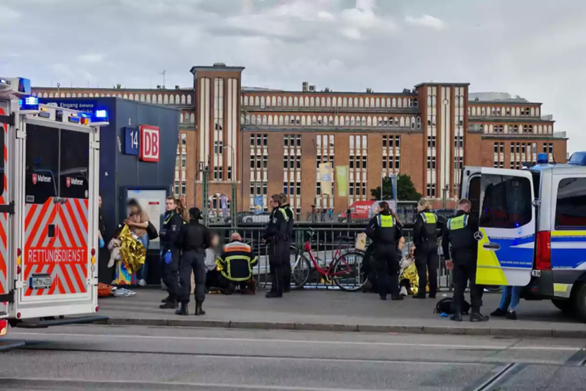 Un grupo de policías y personal de emergencia se encuentra en una estación de tren junto a vehículos de servicio, mientras atienden a varias personas en el lugar. Un grupo de policías y personal de emergencia se encuentra en una estación de tren junto a vehículos de servicio, mientras atienden a varias personas en el lugar.