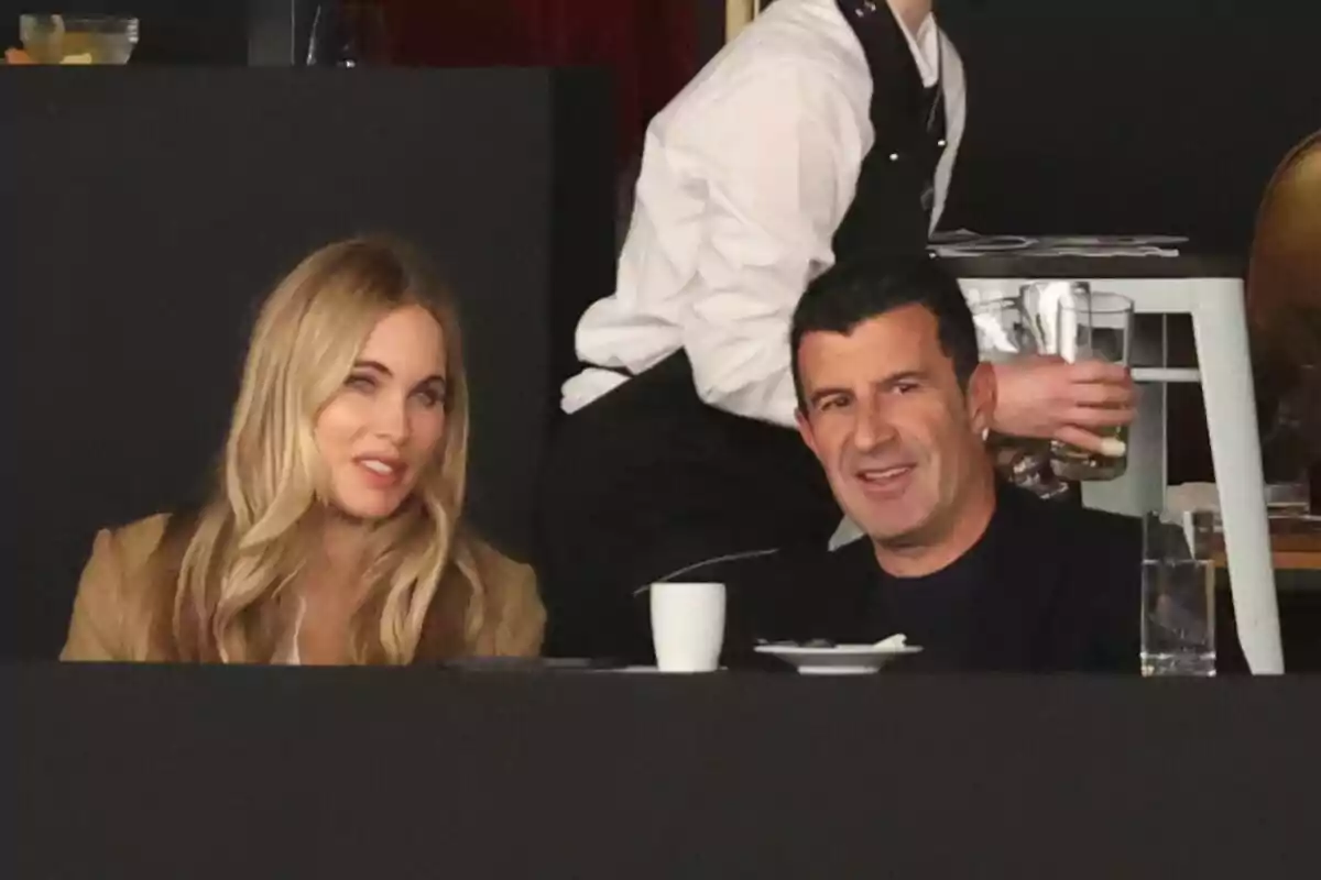Helen Svedin and Luís Figo sitting in a restaurant with a waiter in the background. Helen Svedin and Luís Figo sitting in a restaurant with a waiter in the background.