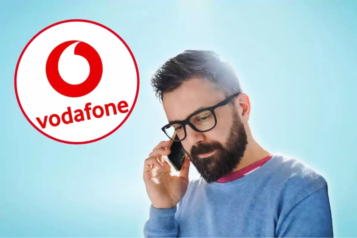 Hombre con barba y gafas hablando por teléfono móvil con el logo de Vodafone en el fondo.