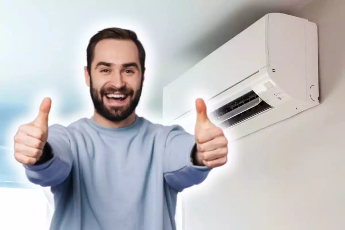 Hombre sonriente con pulgares arriba frente a un aire acondicionado en la pared.