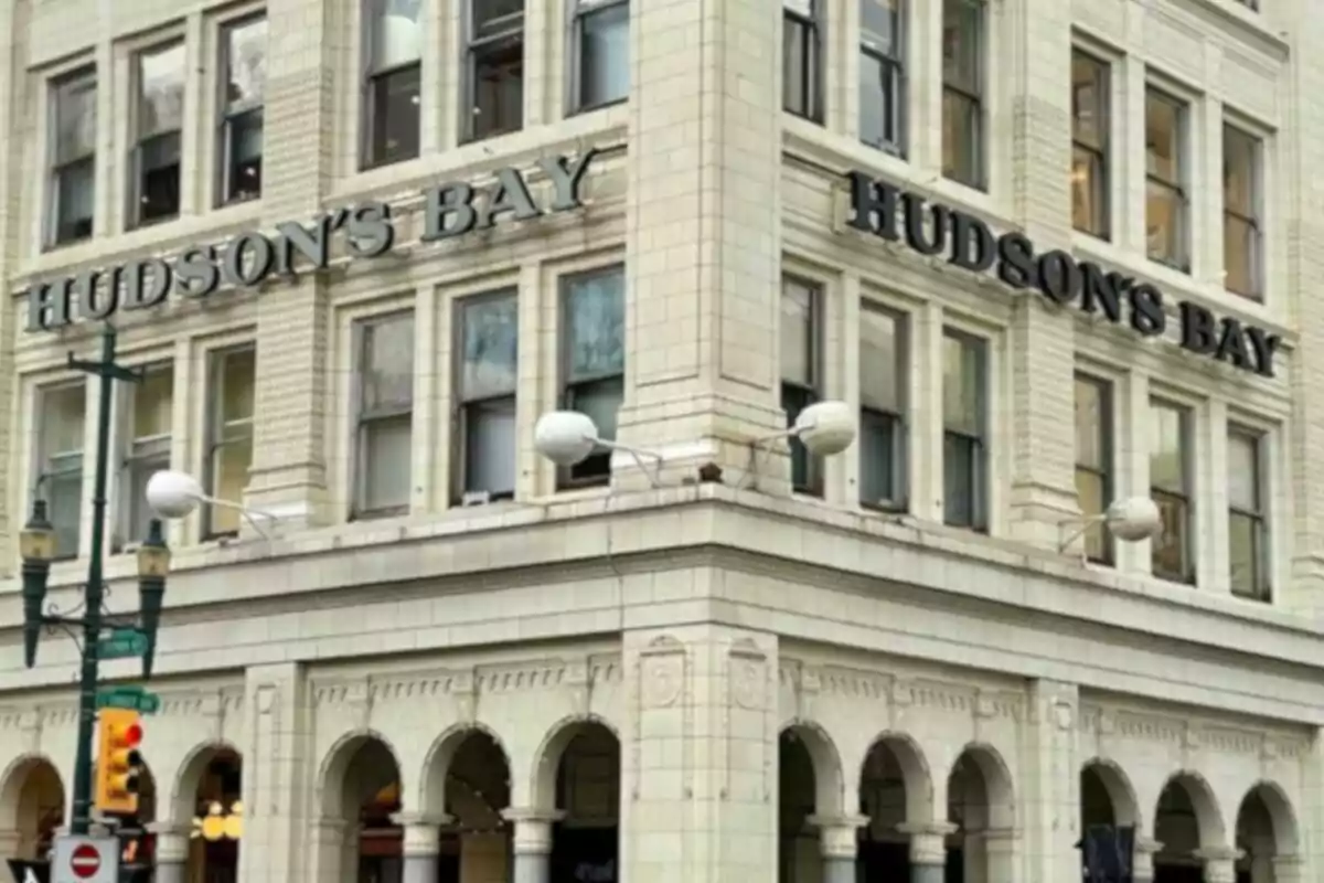 Old multi-story building with signs that say Hudson's Bay and a light-colored facade with arches on the ground floor Old multi-story building with signs that say Hudson's Bay and a light-colored facade with arches on the ground floor
