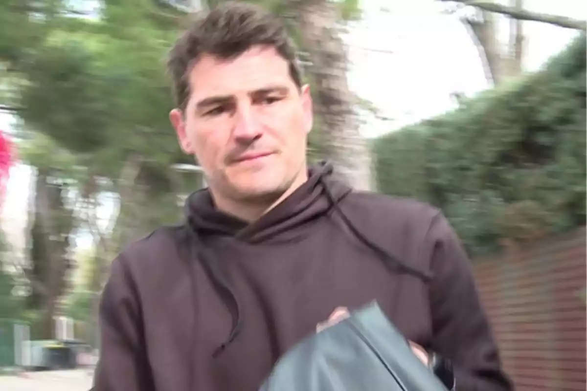 Iker Casillas con sudadera marrón camina al aire libre con árboles de fondo. Iker Casillas con sudadera marrón camina al aire libre con árboles de fondo.