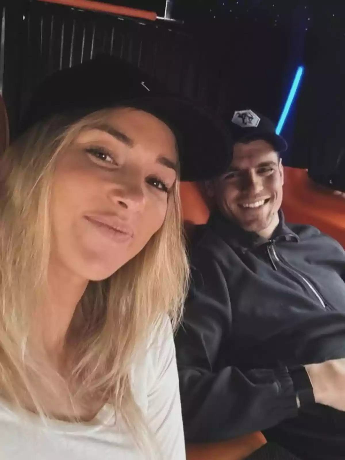 Alice Campello y Álvaro Morata sonríen mientras se toman una selfie en un ambiente oscuro con luces de neón. Alice Campello y Álvaro Morata sonríen mientras se toman una selfie en un ambiente oscuro con luces de neón.