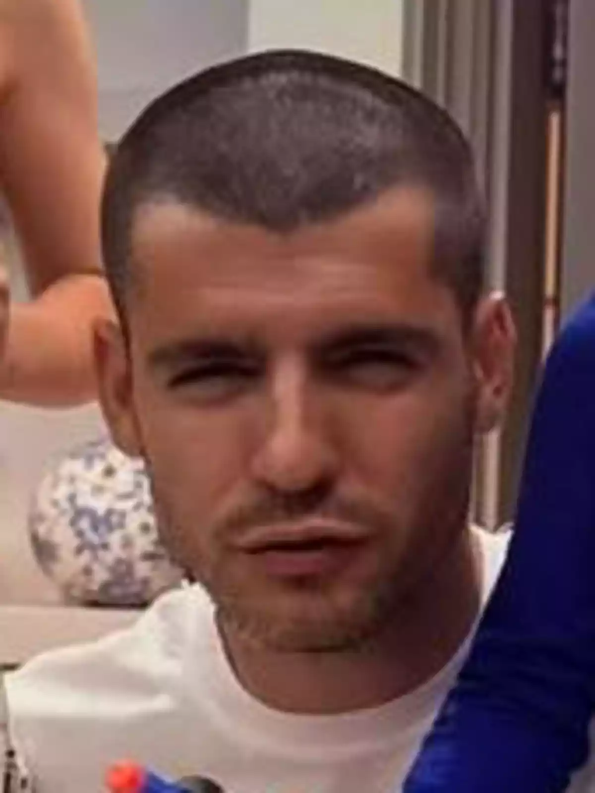 Álvaro Morata con el cabello corto y barba ligera, vistiendo una camiseta blanca, está mirando hacia la cámara. Álvaro Morata con el cabello corto y barba ligera, vistiendo una camiseta blanca, está mirando hacia la cámara.