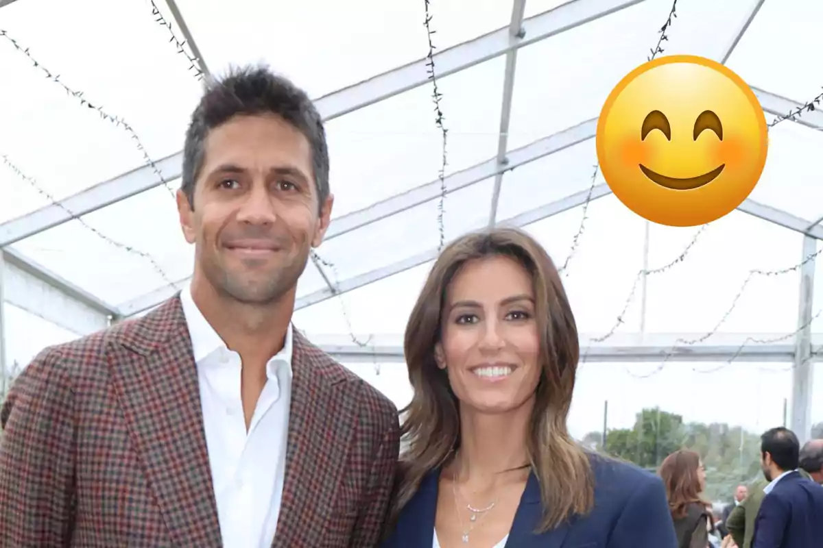 Ana Boyer y Fernando Verdasco sonriendo bajo una carpa transparente con un emoji sonriente grande en la esquina superior derecha