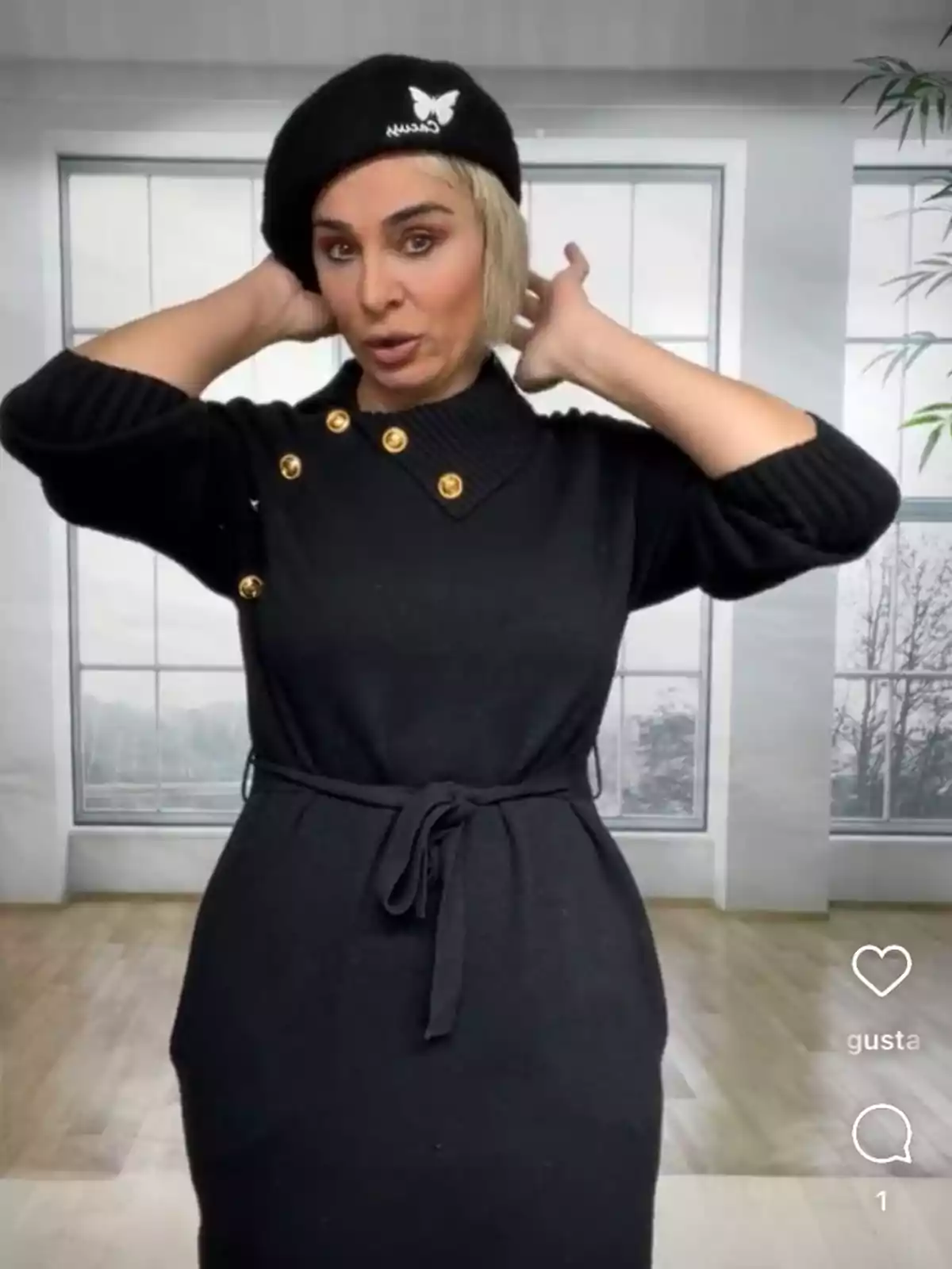 Ana María Aldón con un vestido negro y boina posa frente a una ventana grande en una habitación iluminada. Ana María Aldón con un vestido negro y boina posa frente a una ventana grande en una habitación iluminada.