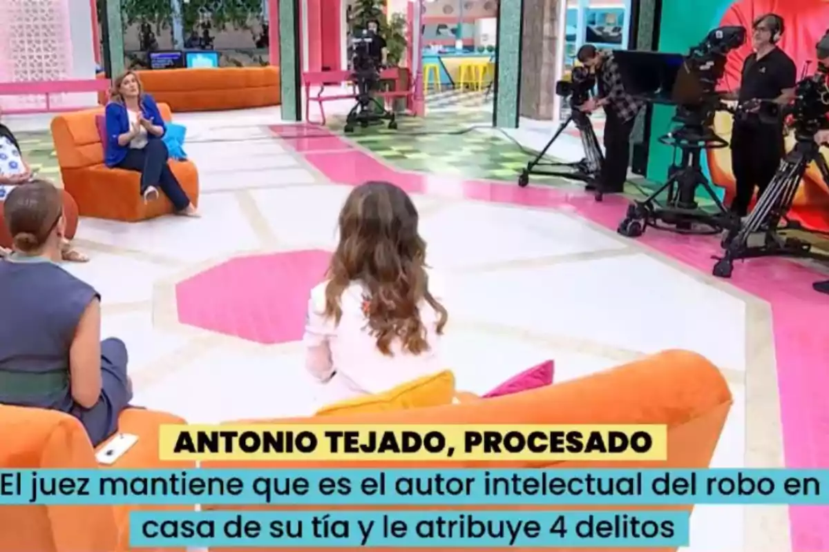 Un grupo de personas está en un set de televisión colorido, con cámaras y equipo de grabación alrededor, mientras un texto en la parte inferior menciona un caso judicial. Un grupo de personas está en un set de televisión colorido, con cámaras y equipo de grabación alrededor, mientras un texto en la parte inferior menciona un caso judicial.