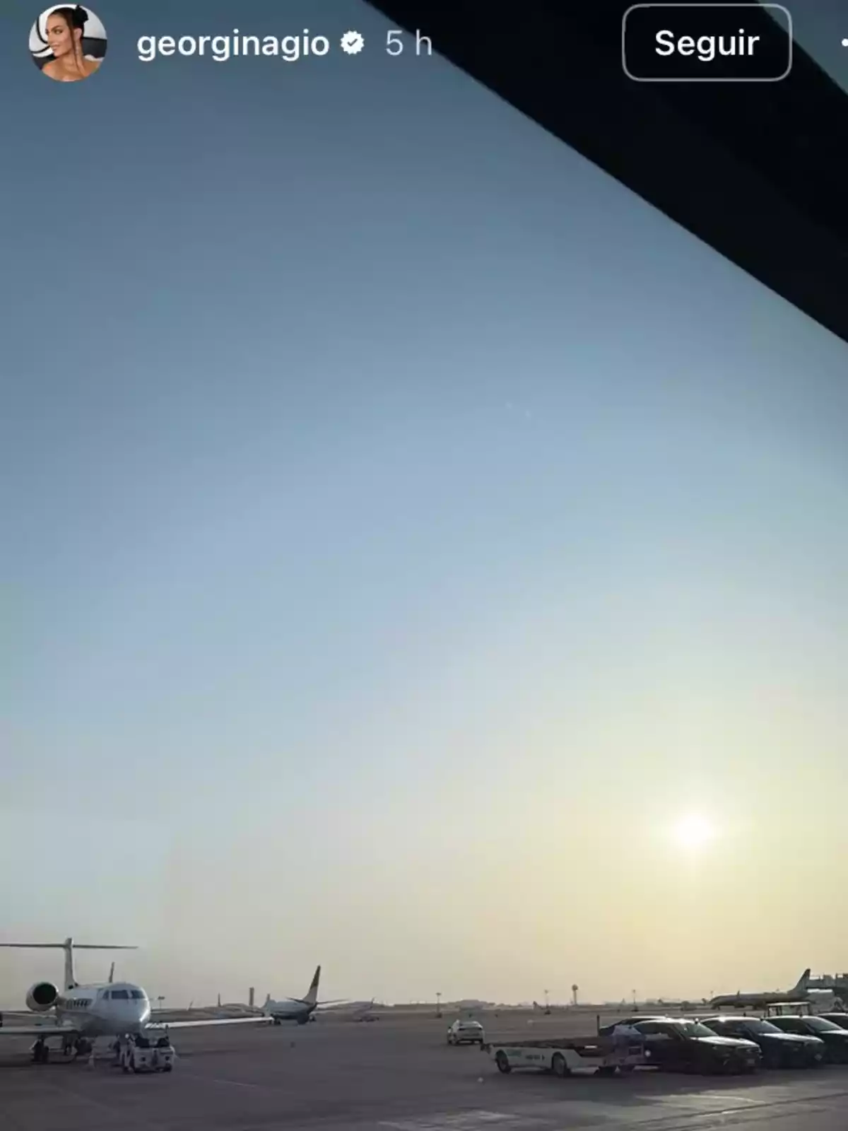 Planes parked on an airport runway at sunset with a clear sky