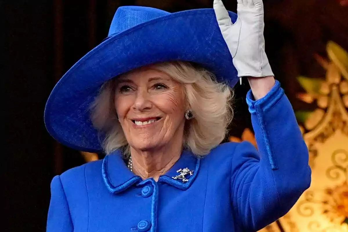 Una mujer sonriente con sombrero y abrigo azul saludando con la mano. Una mujer sonriente con sombrero y abrigo azul saludando con la mano.
