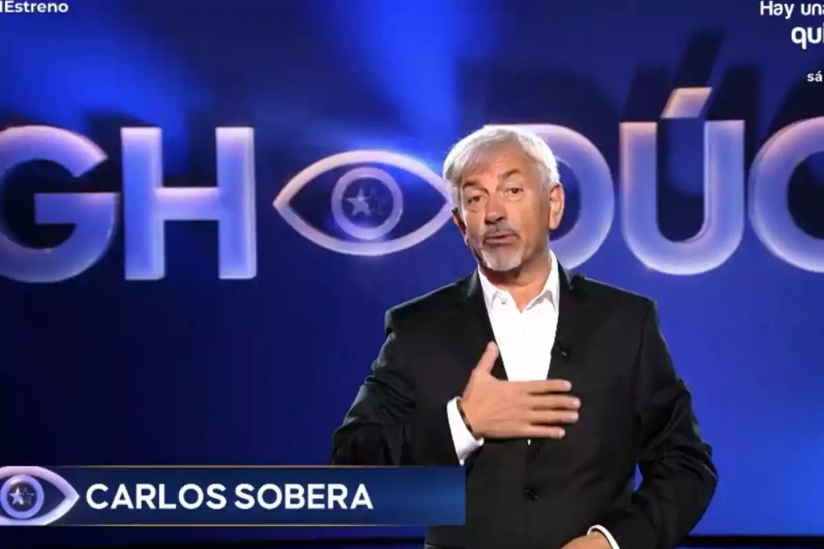 Carlos Sobera en un set con un fondo azul y letras grandes.