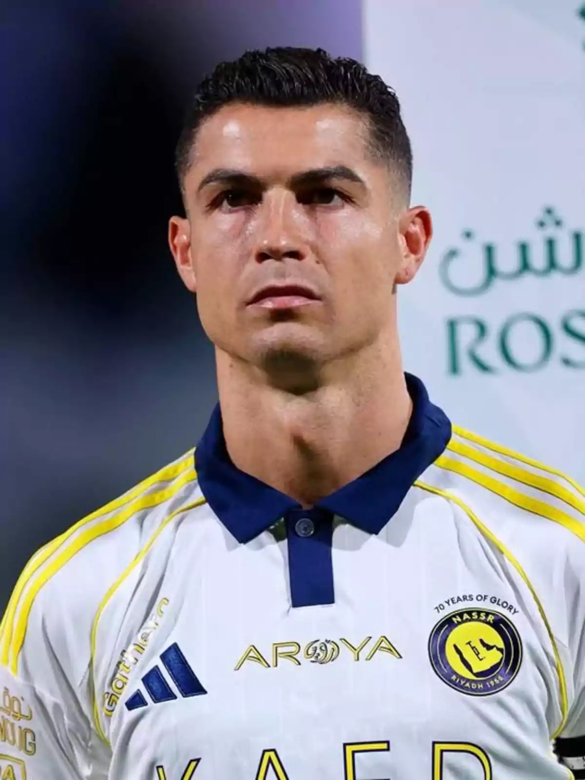 Soccer player wearing a white uniform with yellow details from a Saudi team looking forward during a sporting event
