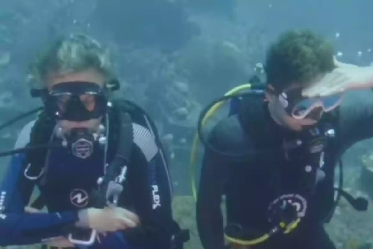 Jesús Calleja y David Bisbal buceando bajo el agua con equipo de buceo, una de ellas se cubre los ojos con la mano. Jesús Calleja y David Bisbal buceando bajo el agua con equipo de buceo, una de ellas se cubre los ojos con la mano.