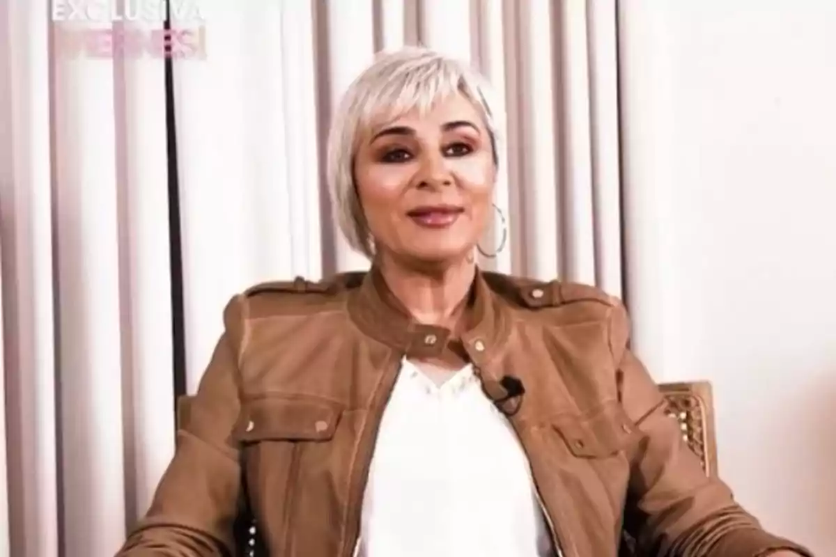 Ana María Aldón con cabello corto y canoso lleva una chaqueta marrón y está sentada frente a unas cortinas claras. Ana María Aldón con cabello corto y canoso lleva una chaqueta marrón y está sentada frente a unas cortinas claras.