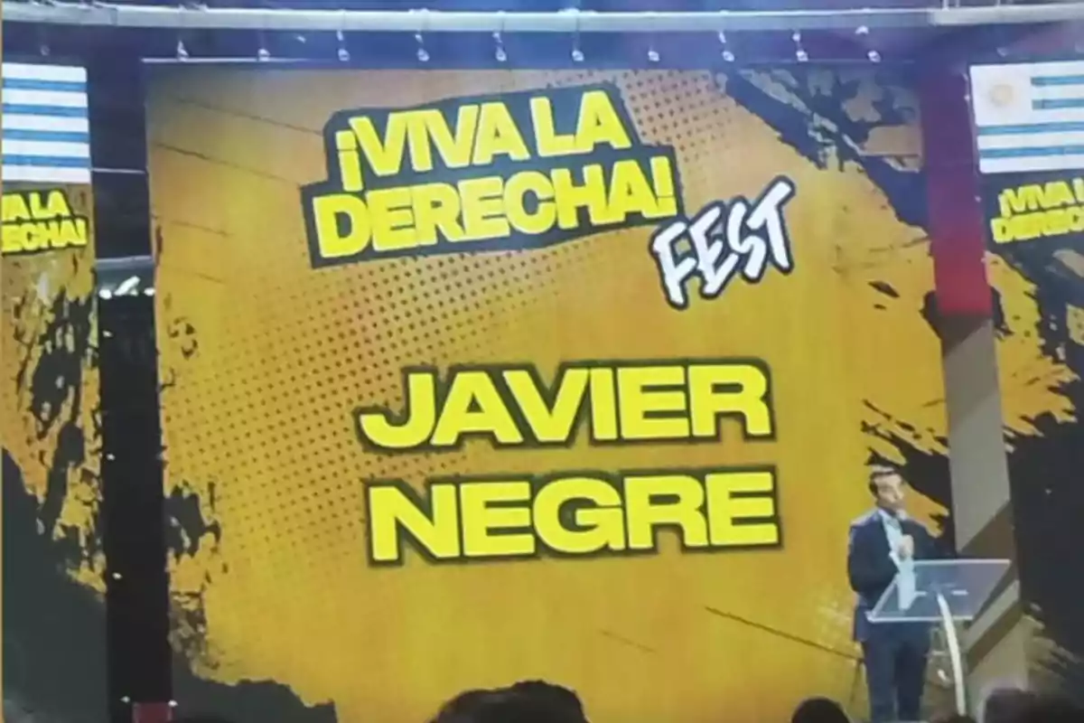 Una persona en un escenario con un fondo amarillo que dice Una persona en un escenario con un fondo amarillo que dice