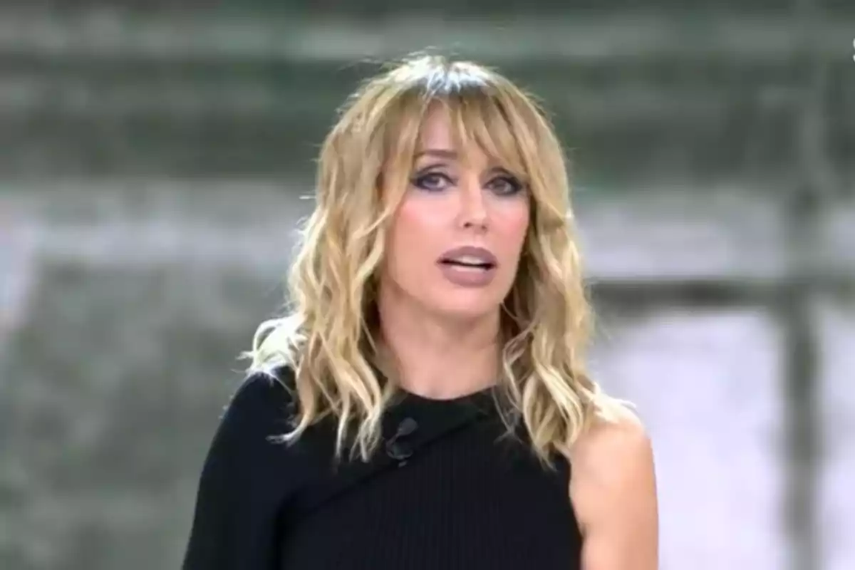 Emma García con cabello rubio y ondulado lleva un vestido negro de un solo hombro mientras mira hacia adelante. Emma García con cabello rubio y ondulado lleva un vestido negro de un solo hombro mientras mira hacia adelante.