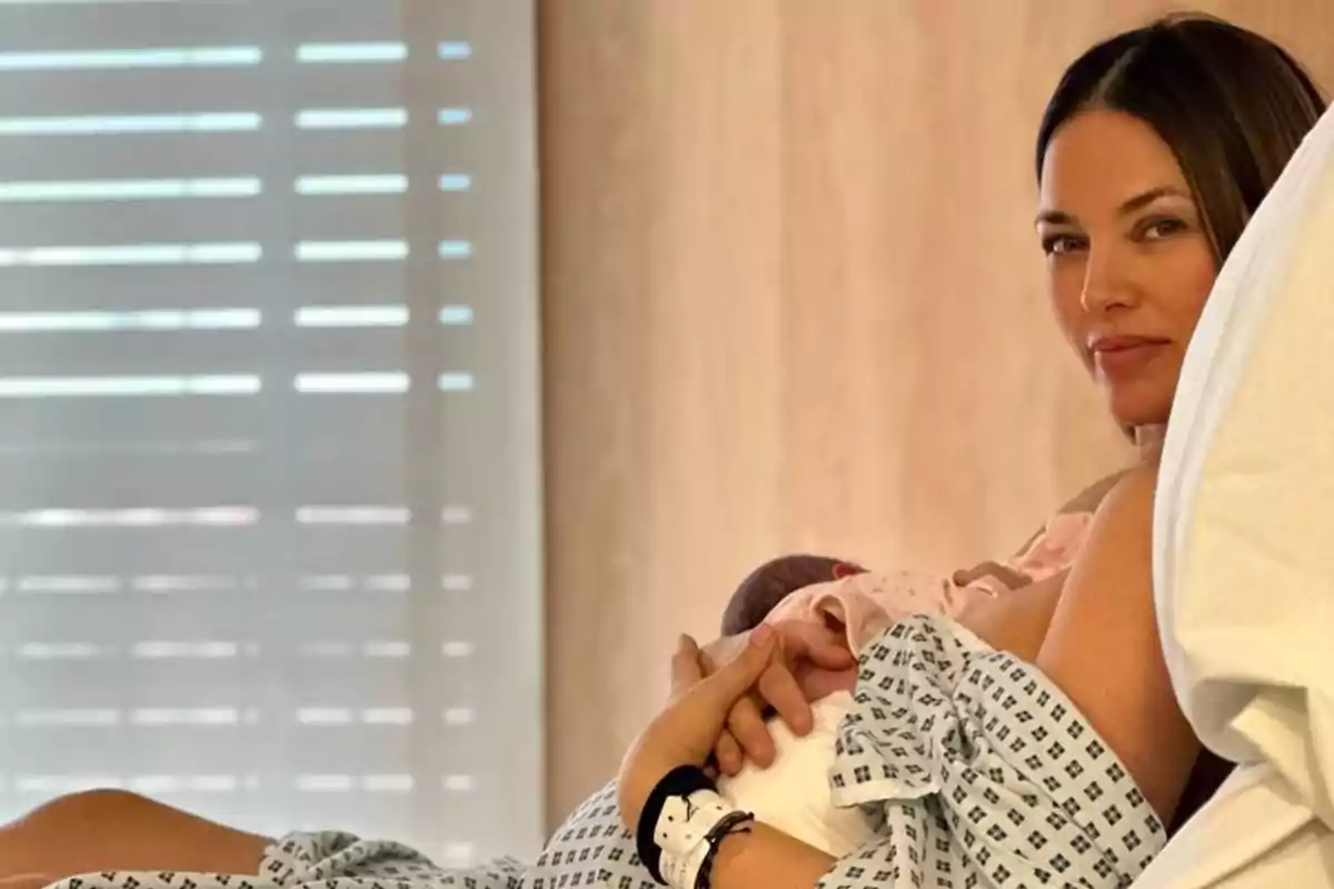 Helen Lindes en una cama de hospital sosteniendo a un bebé. Helen Lindes en una cama de hospital sosteniendo a un bebé.