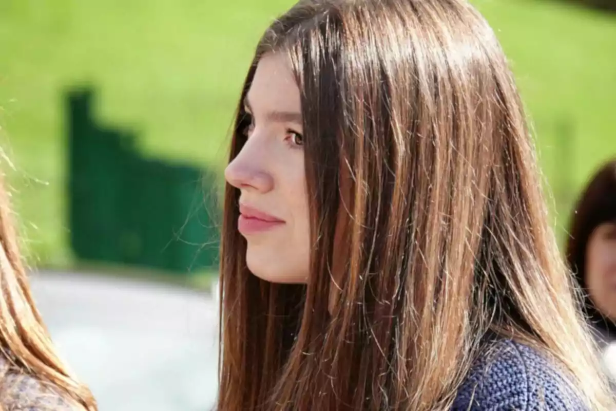A young woman in profile with long brown hair in an outdoor setting. A young woman in profile with long brown hair in an outdoor setting.