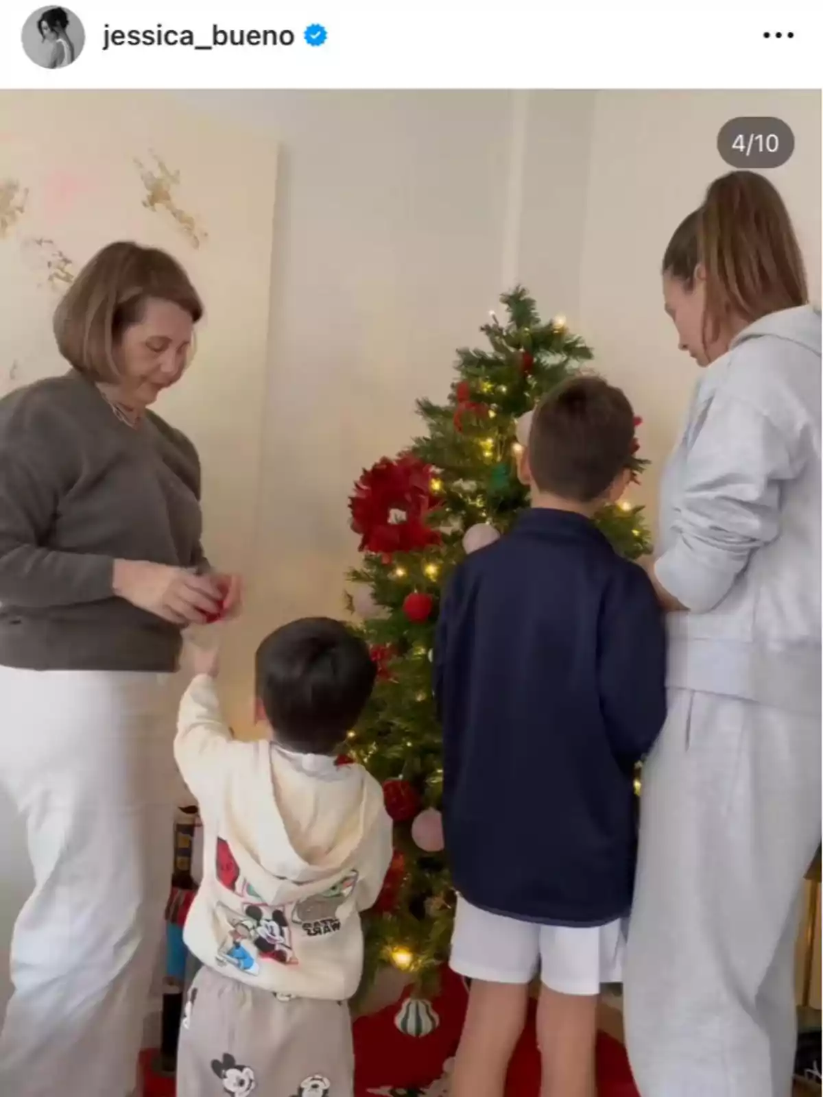 Una familia decorando un árbol de Navidad juntos en una sala iluminada. Una familia decorando un árbol de Navidad juntos en una sala iluminada.