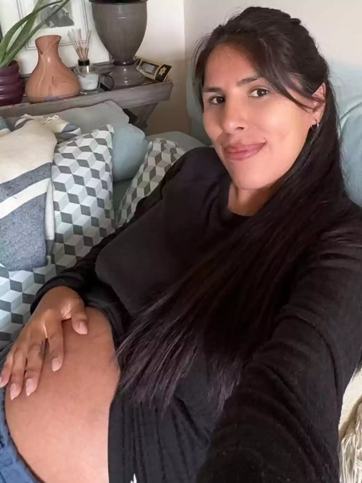 Isa Pantoja embarazada sonríe mientras se toma una selfie en un sofá rodeada de cojines. Isa Pantoja embarazada sonríe mientras se toma una selfie en un sofá rodeada de cojines.