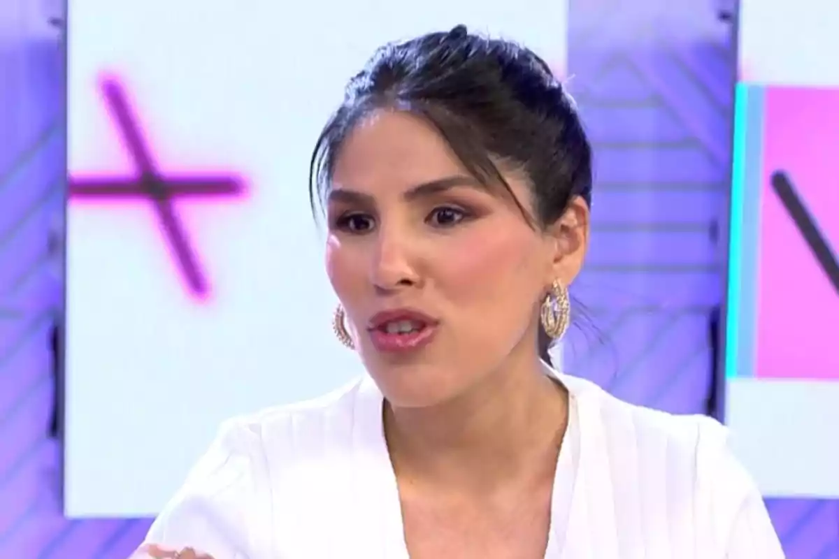 Isa Pantoja con el cabello recogido y pendientes grandes habla en un entorno de estudio con luces de colores. Isa Pantoja con el cabello recogido y pendientes grandes habla en un entorno de estudio con luces de colores.