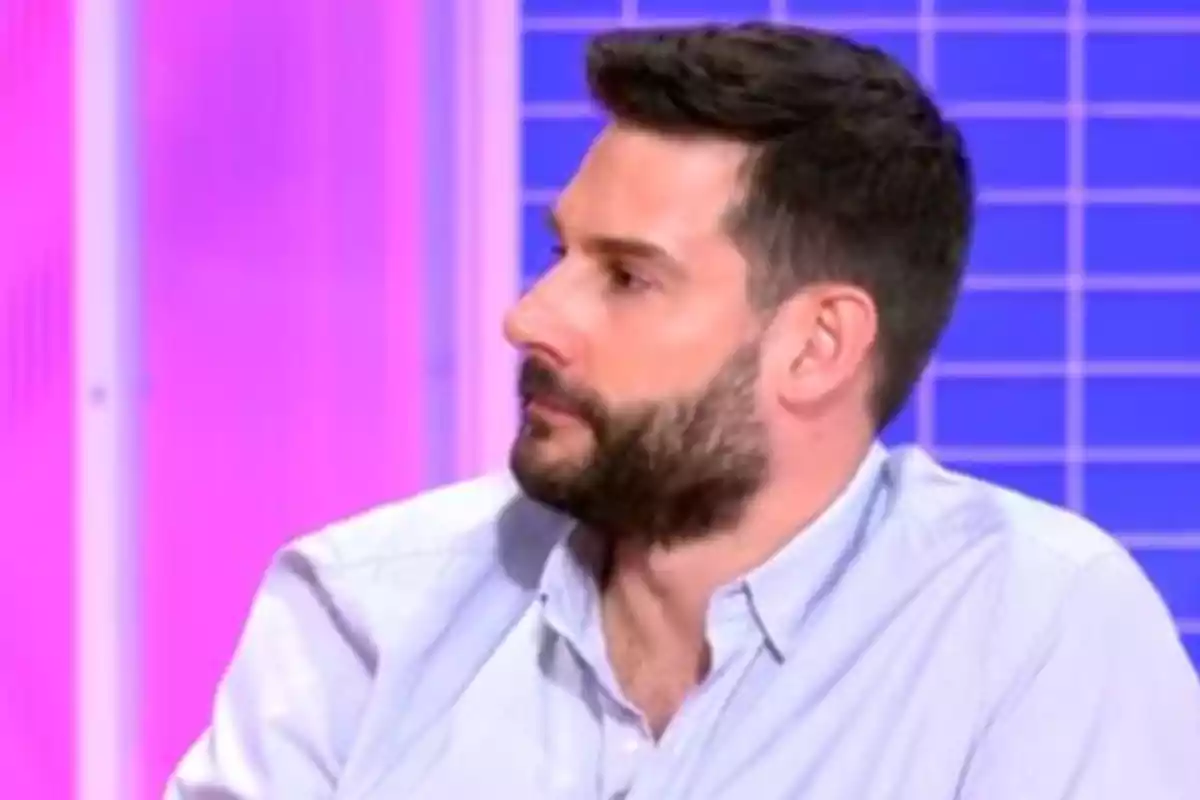 Iván García con barba y camisa clara mira hacia un lado con un fondo de colores brillantes. Iván García con barba y camisa clara mira hacia un lado con un fondo de colores brillantes.