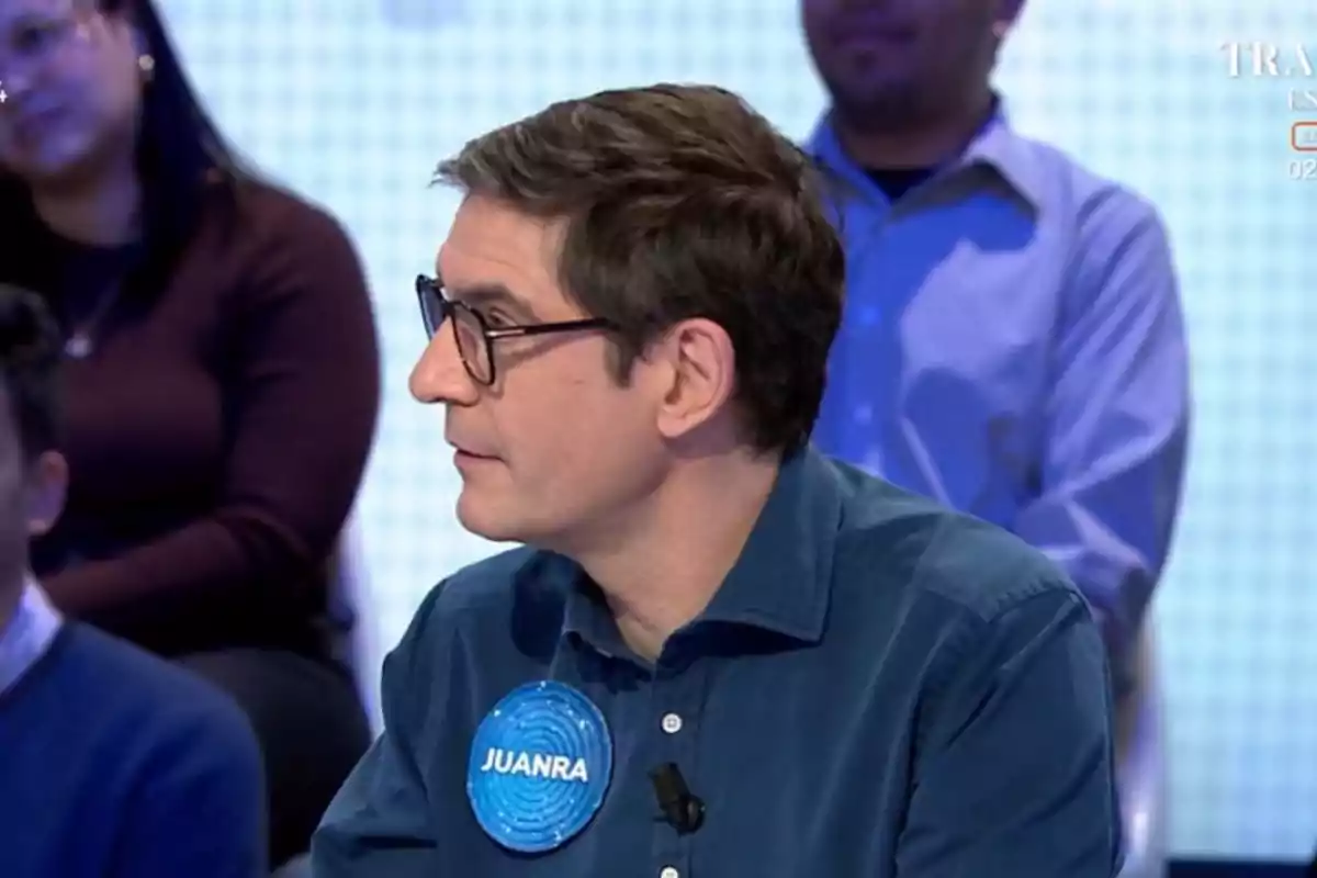 Juanra Bonet con gafas y camisa azul participa en un programa de televisión, con personas sentadas al fondo. Juanra Bonet con gafas y camisa azul participa en un programa de televisión, con personas sentadas al fondo.