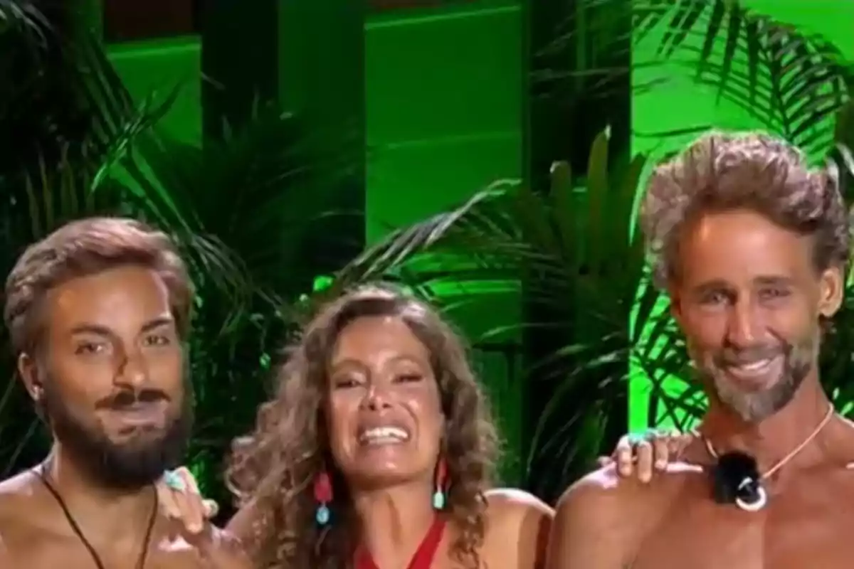 Borja González, Laura Madrueño y Álvaro Muñoz Escassi sonríen frente a un fondo verde con plantas, dos hombres sin camiseta y una mujer en el centro con pendientes coloridos. Borja González, Laura Madrueño y Álvaro Muñoz Escassi sonríen frente a un fondo verde con plantas, dos hombres sin camiseta y una mujer en el centro con pendientes coloridos.