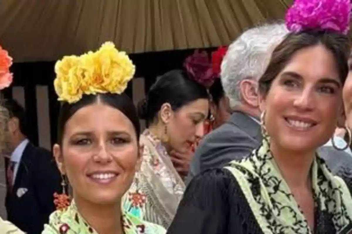 Lourdes Montes y Tana Rivera vestidas con trajes tradicionales y flores en el cabello en un evento al aire libre. Lourdes Montes y Tana Rivera vestidas con trajes tradicionales y flores en el cabello en un evento al aire libre.