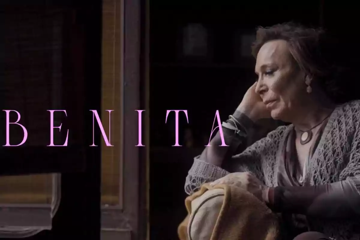 Benita mayor sentada junto a una ventana con expresión pensativa y la palabra BENITA en letras grandes de color rosa Benita mayor sentada junto a una ventana con expresión pensativa y la palabra BENITA en letras grandes de color rosa