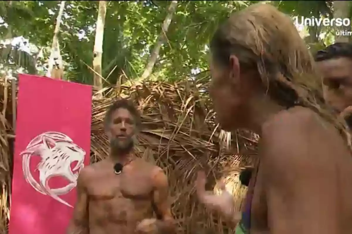 Makoke y Álvaro Muñoz Escassi discuten en un entorno selvático con un cartel rosa y un símbolo de felino en el fondo. Makoke y Álvaro Muñoz Escassi discuten en un entorno selvático con un cartel rosa y un símbolo de felino en el fondo.