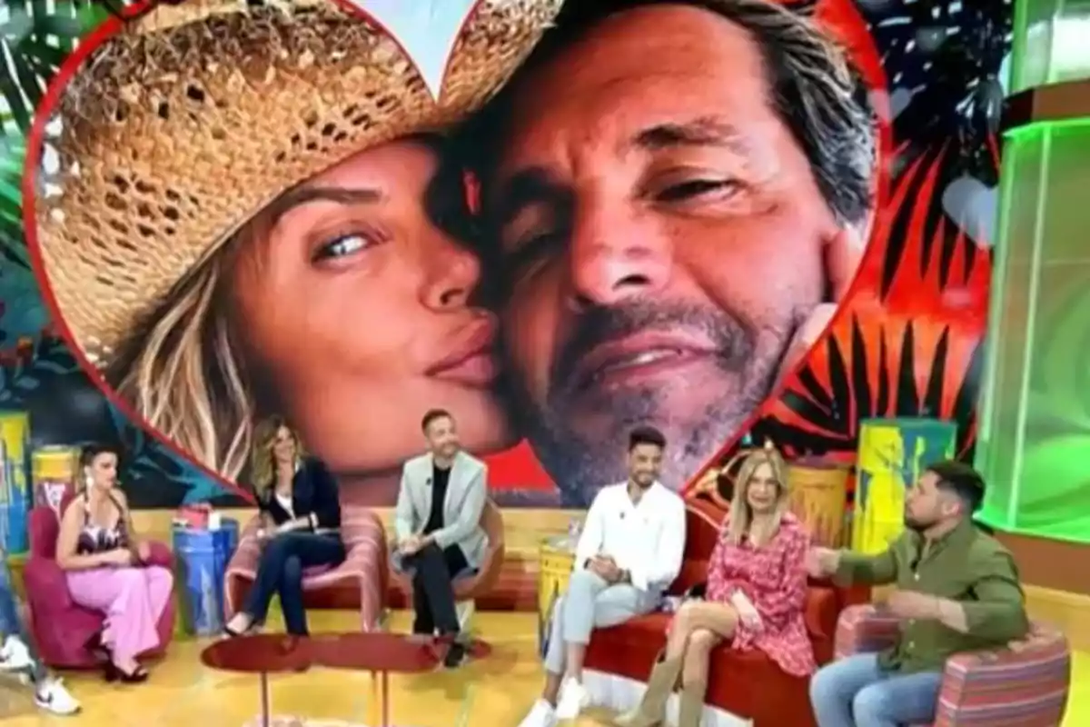 Un grupo de personas está sentado en un set de televisión con una gran imagen de fondo que muestra a una pareja dentro de un corazón. Un grupo de personas está sentado en un set de televisión con una gran imagen de fondo que muestra a una pareja dentro de un corazón.