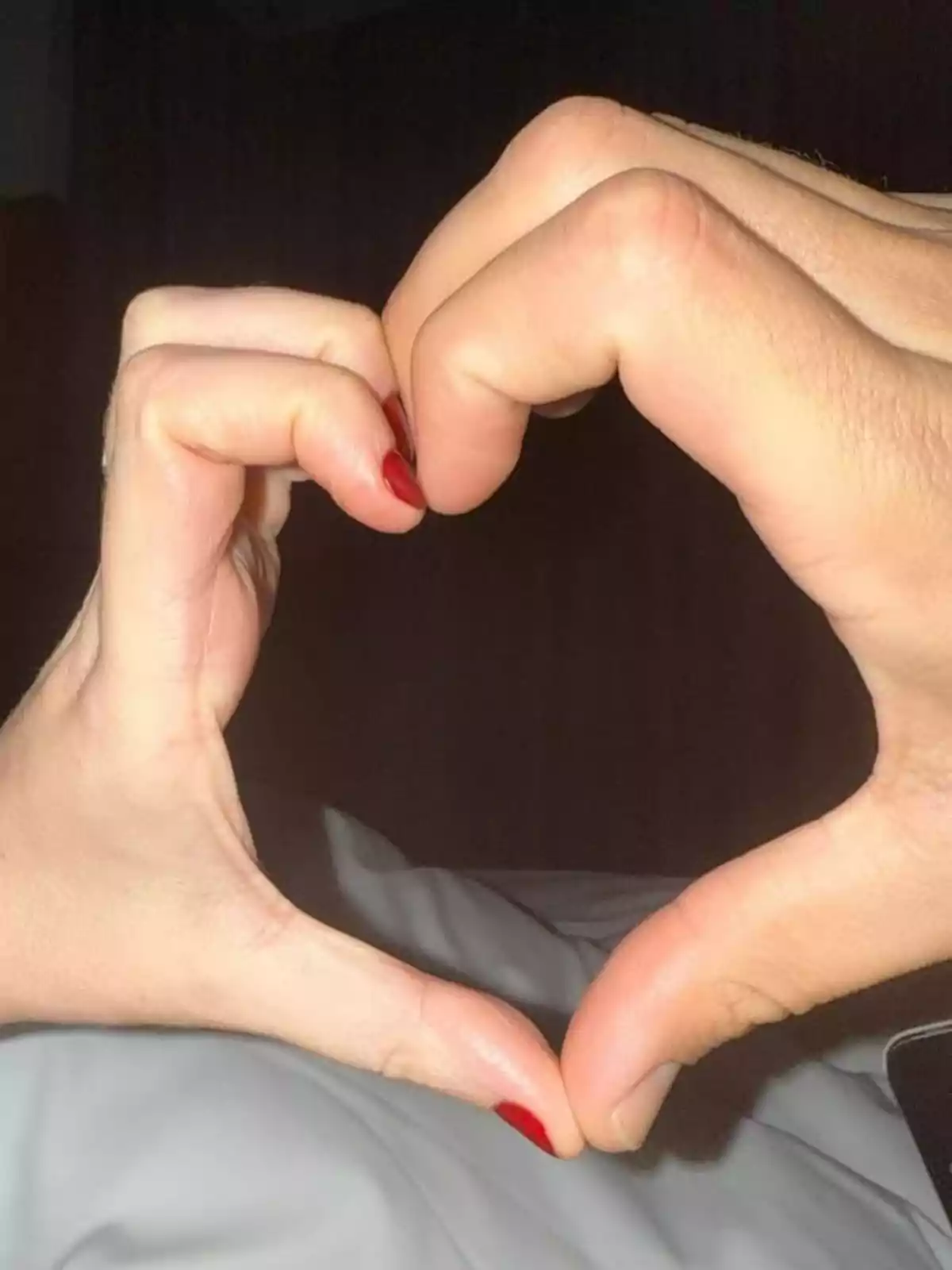 Dos manos formando un corazón juntas sobre un fondo oscuro. Dos manos formando un corazón juntas sobre un fondo oscuro.