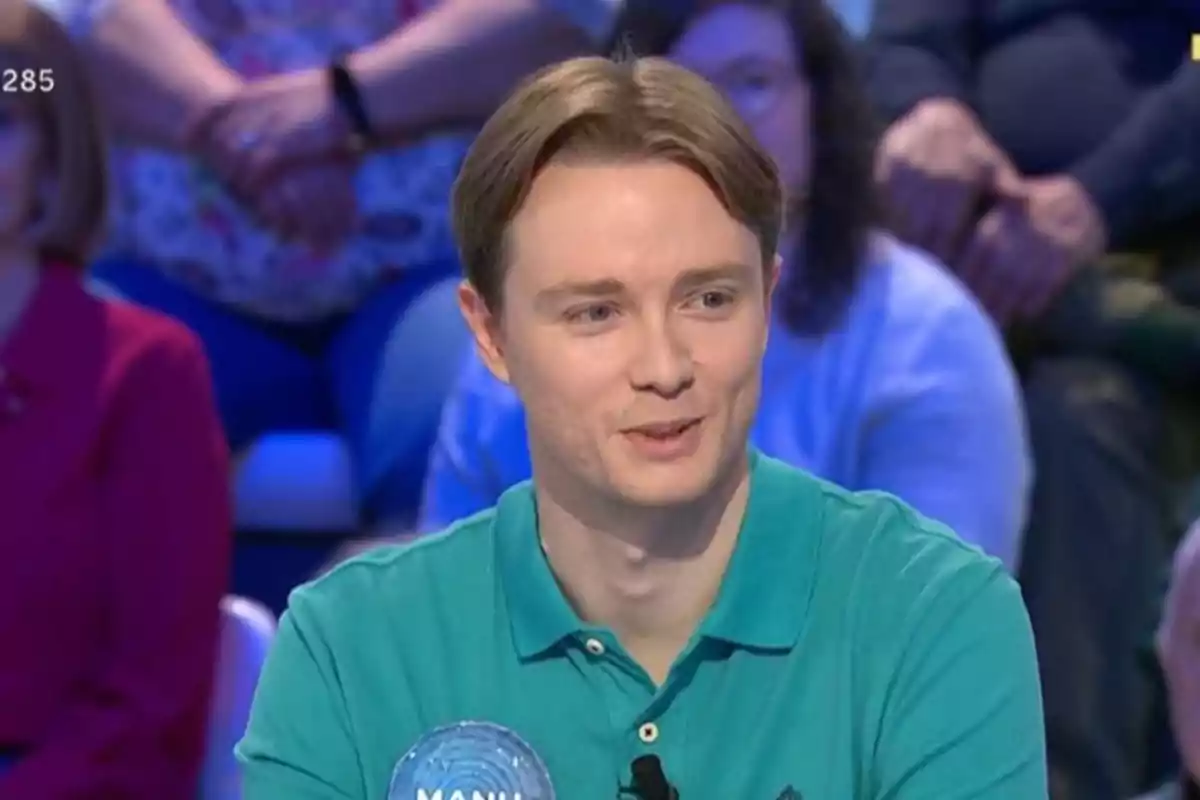 Manu joven con camisa verde sonríe mientras participa en un programa de televisión con público al fondo. Manu joven con camisa verde sonríe mientras participa en un programa de televisión con público al fondo.