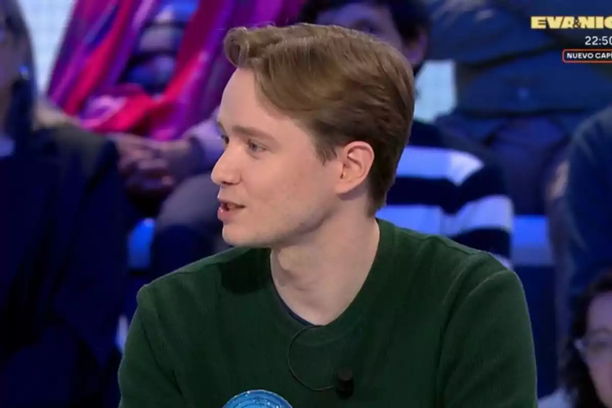 Manu joven con suéter verde está participando en un programa de televisión, hablando mientras está sentado en un estudio con público de fondo. Manu joven con suéter verde está participando en un programa de televisión, hablando mientras está sentado en un estudio con público de fondo.