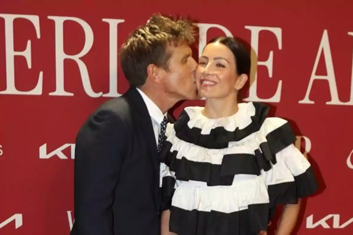 Manuel Díaz ‘El Cordobés’ besa en la mejilla a Virginia Troconis sonriente frente a un fondo rojo con letras blancas. Manuel Díaz ‘El Cordobés’ besa en la mejilla a Virginia Troconis sonriente frente a un fondo rojo con letras blancas.