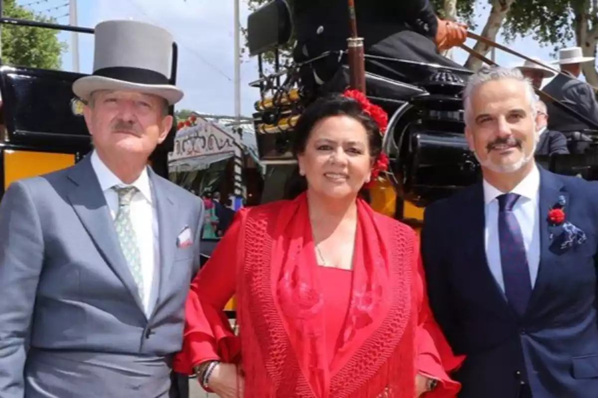 Tres personas posan elegantemente vestidas frente a un carruaje en un evento al aire libre. Tres personas posan elegantemente vestidas frente a un carruaje en un evento al aire libre.